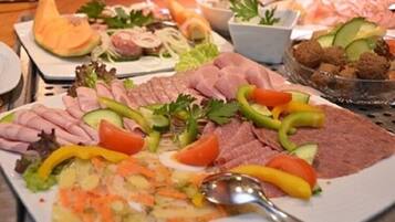 Diversa variedad de alimentos, incluyendo carnes cortadas, verduras y un bol de albóndigas.