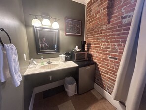 A bathroom with a sink, mirror, and a small trash bin.