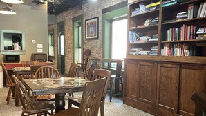 A cozy indoor space with a round table and chairs, a bookshelf with books, and a ceiling fan. - William Watson Hotel (Pittsfield)