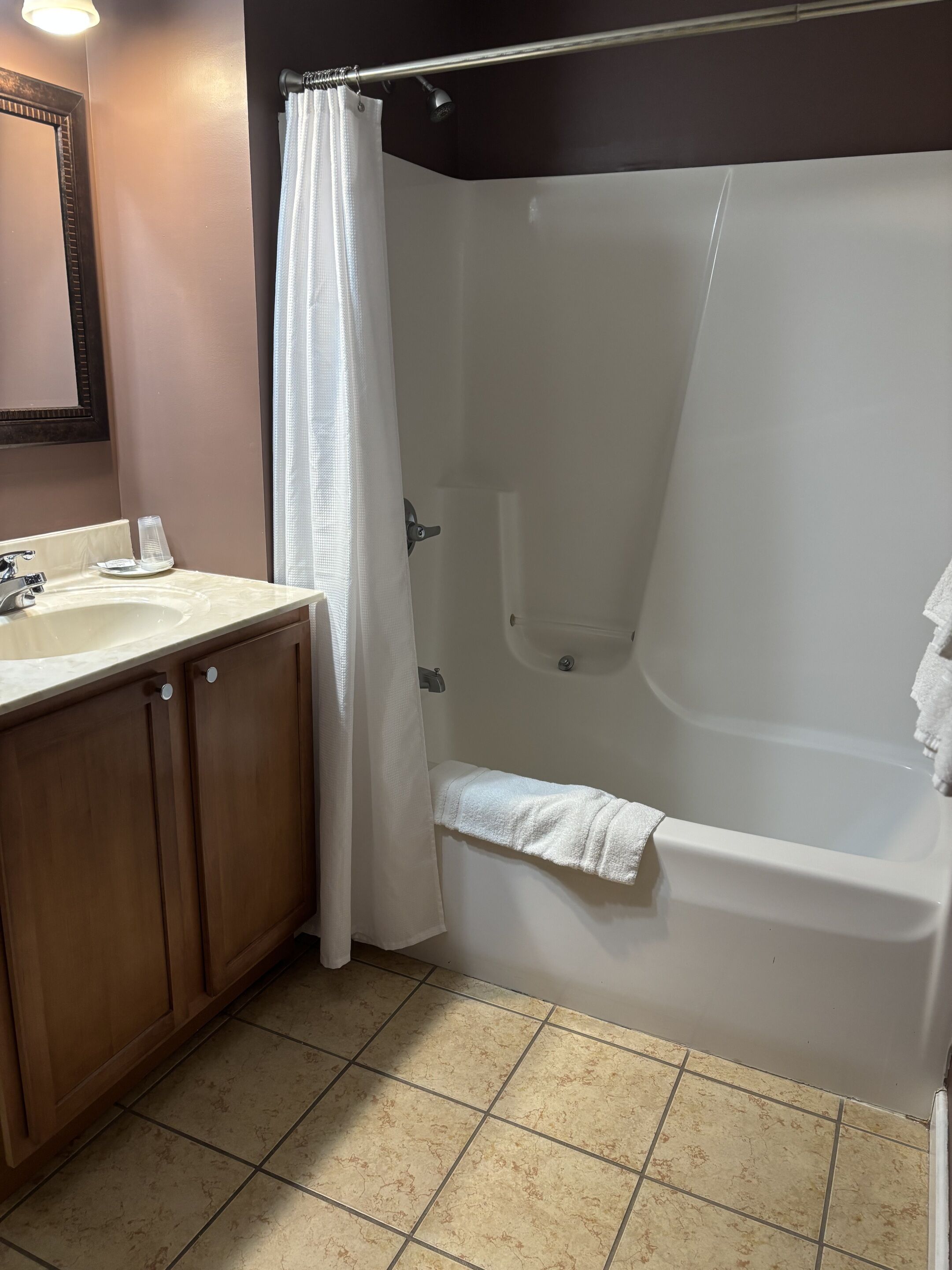 Une salle de bain avec une baignoire, un lavabo et des meubles en bois.
