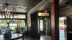 A cozy interior with a round dining table, chairs, a chandelier, and a view through large windows. - William Watson Hotel (Pittsfield)