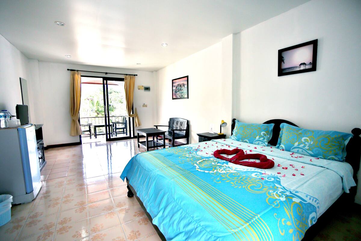 A hotel room with a bed, a desk, a chair, and a balcony.