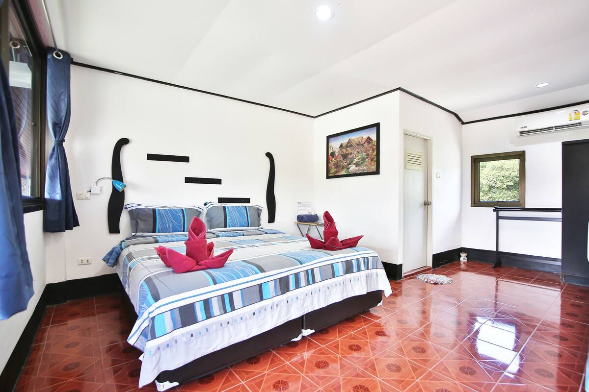 A hotel room with a large bed, a window, and a painting on the wall.