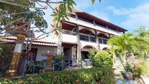 A multi-story building with a balcony, surrounded by lush greenery and a decorative fountain. - Lotus Friendly Hotel (Koh Samui)