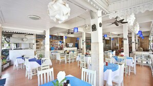 A restaurant with white furniture, blue tablecloths, and hanging decorations. - Lotus Friendly Hotel (Koh Samui)