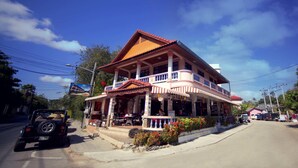 A two-story building with a balcony, a signboard, and a parked vehicle. - Lotus Friendly Hotel (Koh Samui)