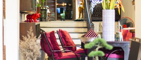 Un coin salon accueillant avec des fauteuils rembourrés de couleur rouge, une petite table et des objets décoratifs, notamment une statue de taureau rouge et un vase avec des plantes.