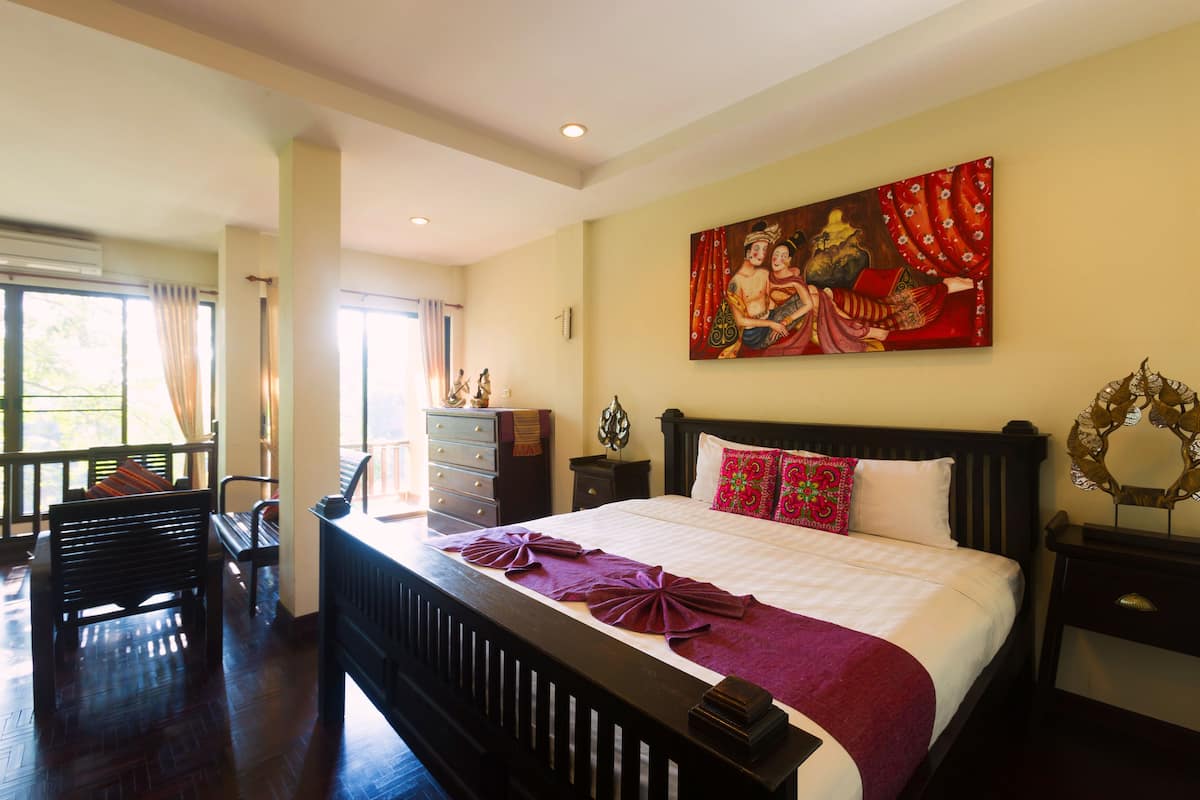 Une chambre d’hôtel avec un grand lit, une table de chevet, une commode, un banc et un tableau au mur.