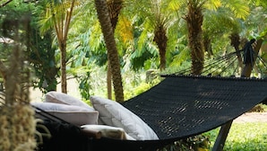 A hammock bed with pillows in a lush garden setting. - Villa San Pee Seua (Chiang Mai)