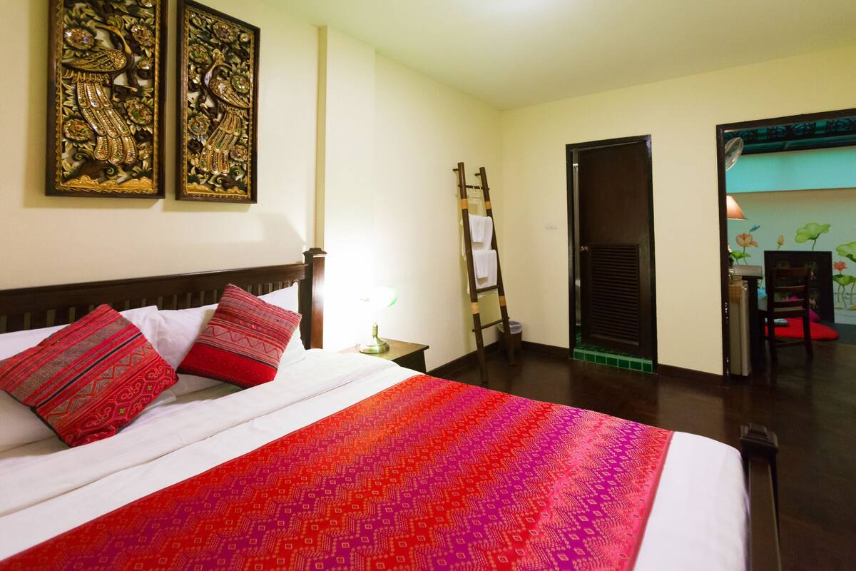 Une chambre d’hôtel avec un lit, une échelle en bois, une porte et un mur orné d’œuvres d’art.