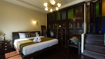 Une chambre d’hôtel avec un grand lit, un lustre, une armoire en bois et un banc.