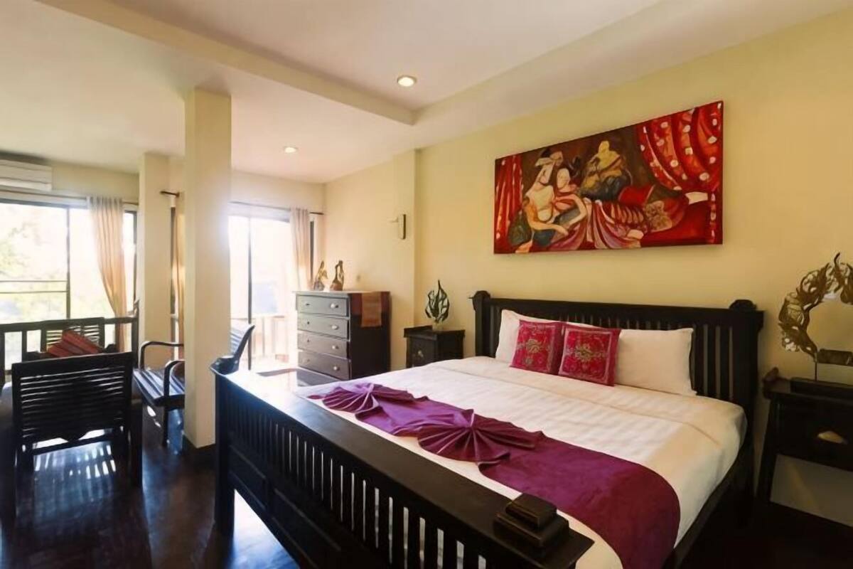 Une chambre d’hôtel avec un grand lit, un bureau, une chaise, une commode et un tableau au mur.