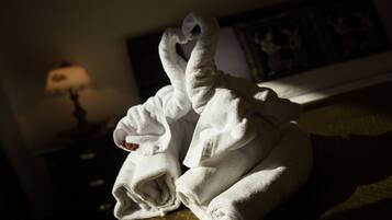 A neatly folded white towel on a bed in a dimly lit room.
