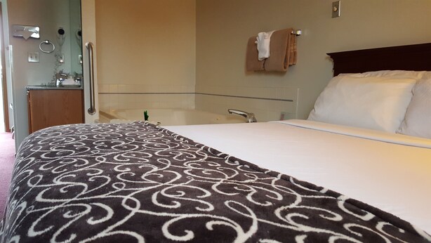 Habitación de hotel con cama, baño y un pequeño escritorio con espejo.