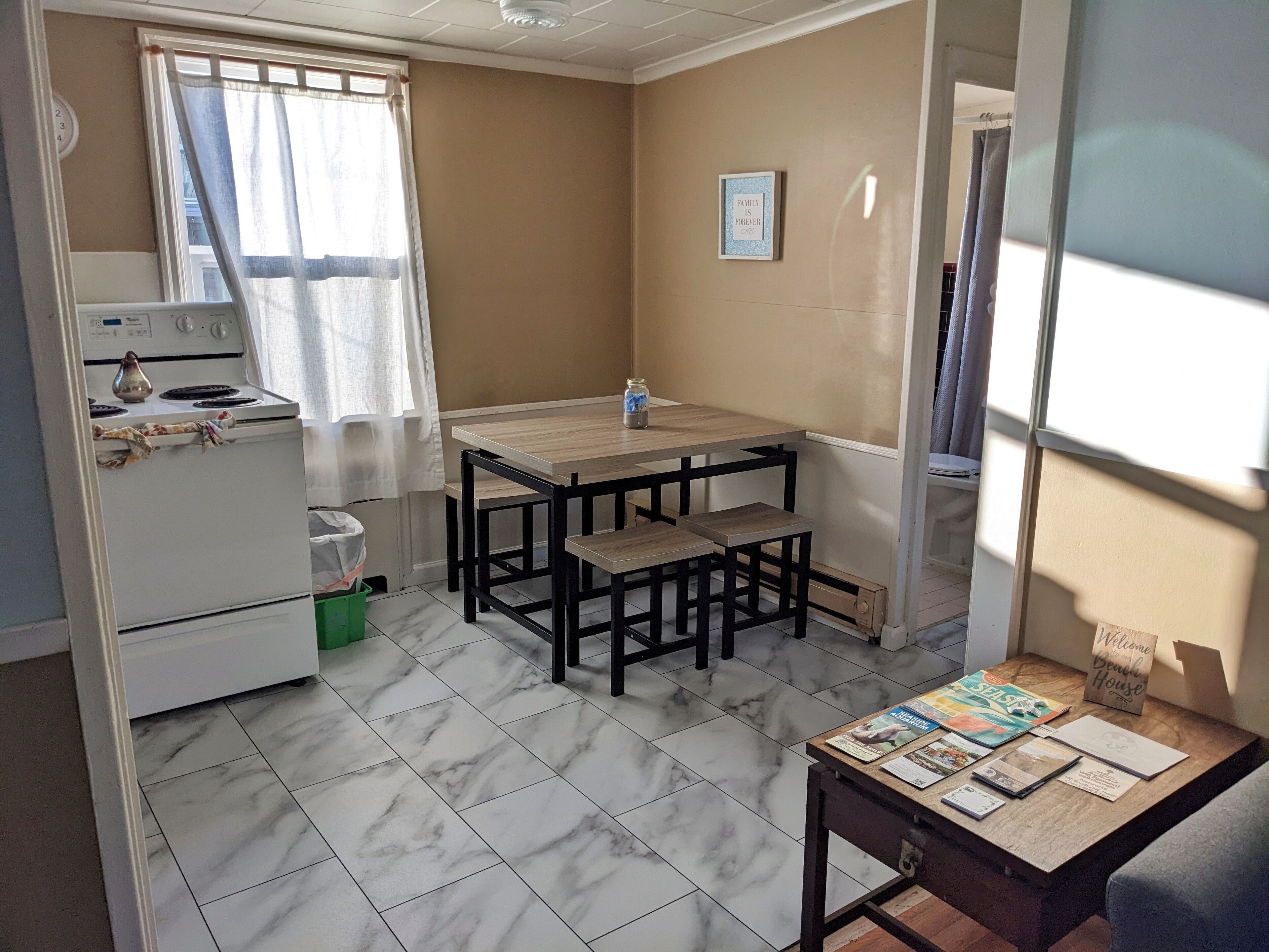 Una cucina compatta con un piano cottura, un tavolo con panche e una finestra con tende.