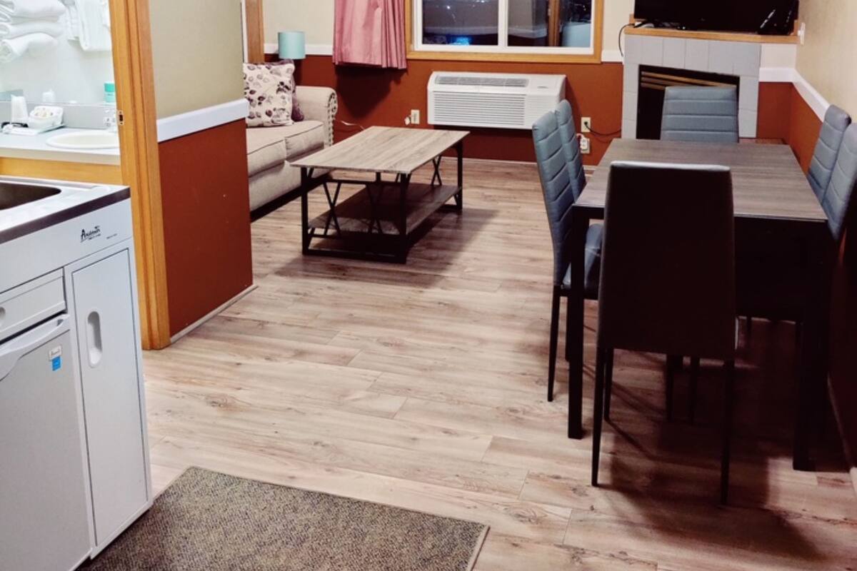 A compact living space with a kitchenette, dining area, and a TV mounted above a fireplace.