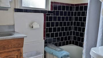 Casa de banho com sanita, lavatório, um contentor de lixo e banheira.