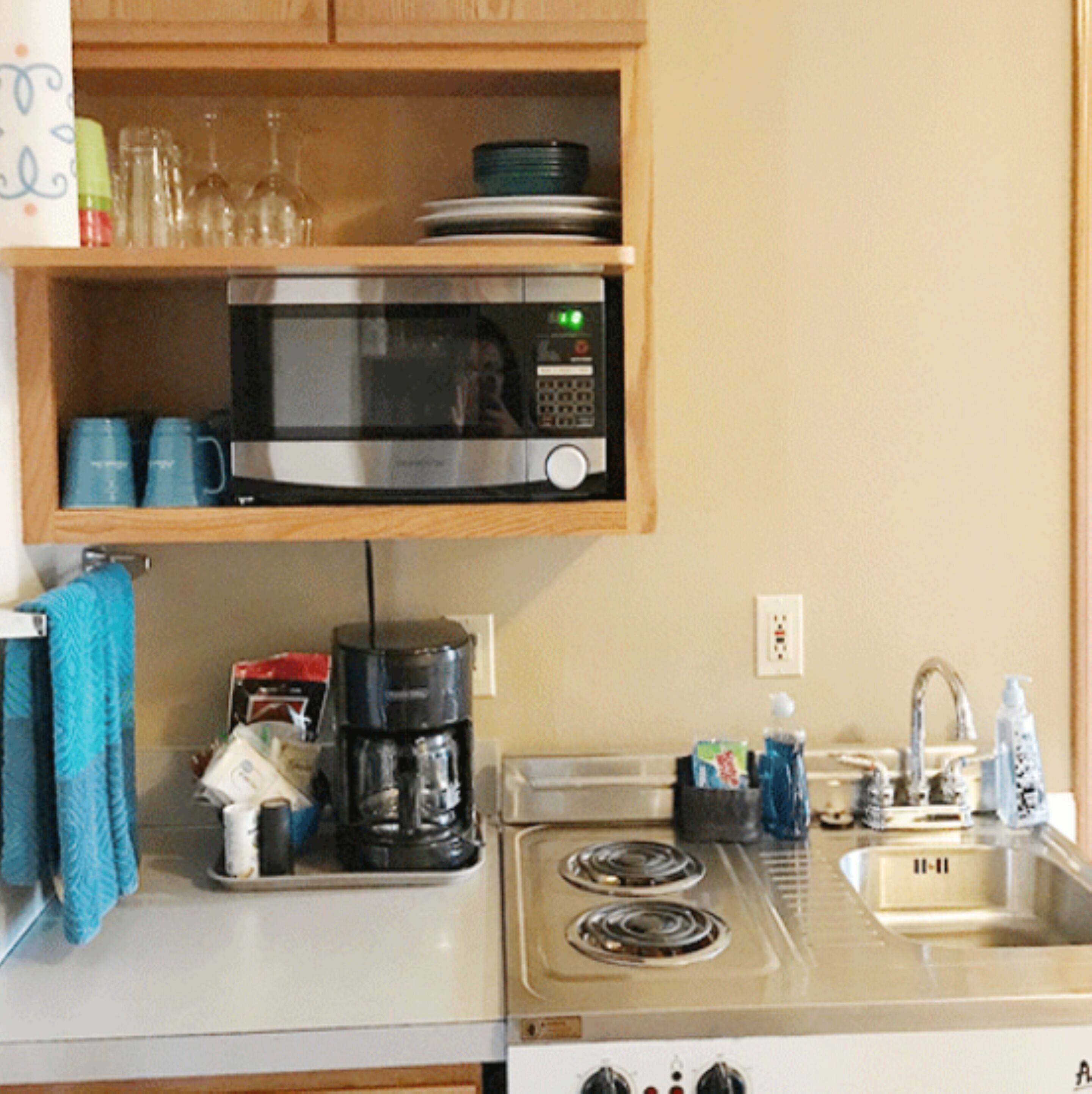 Una cocina equipada con microondas, cafetera, fregadero y estufa.