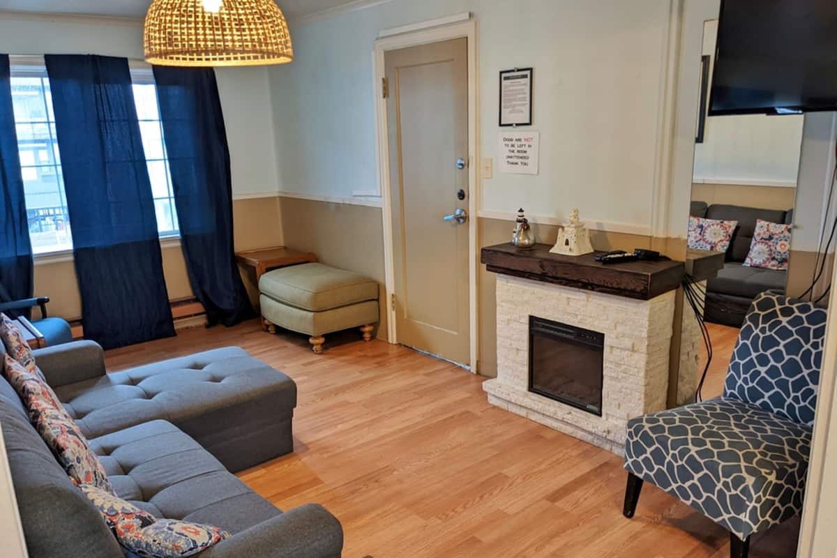 A living room with a sofa, ottoman, fireplace, and a television.