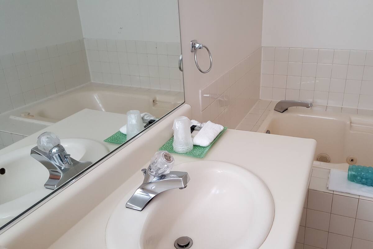 A bathroom with a sink, mirror, and bathtub.