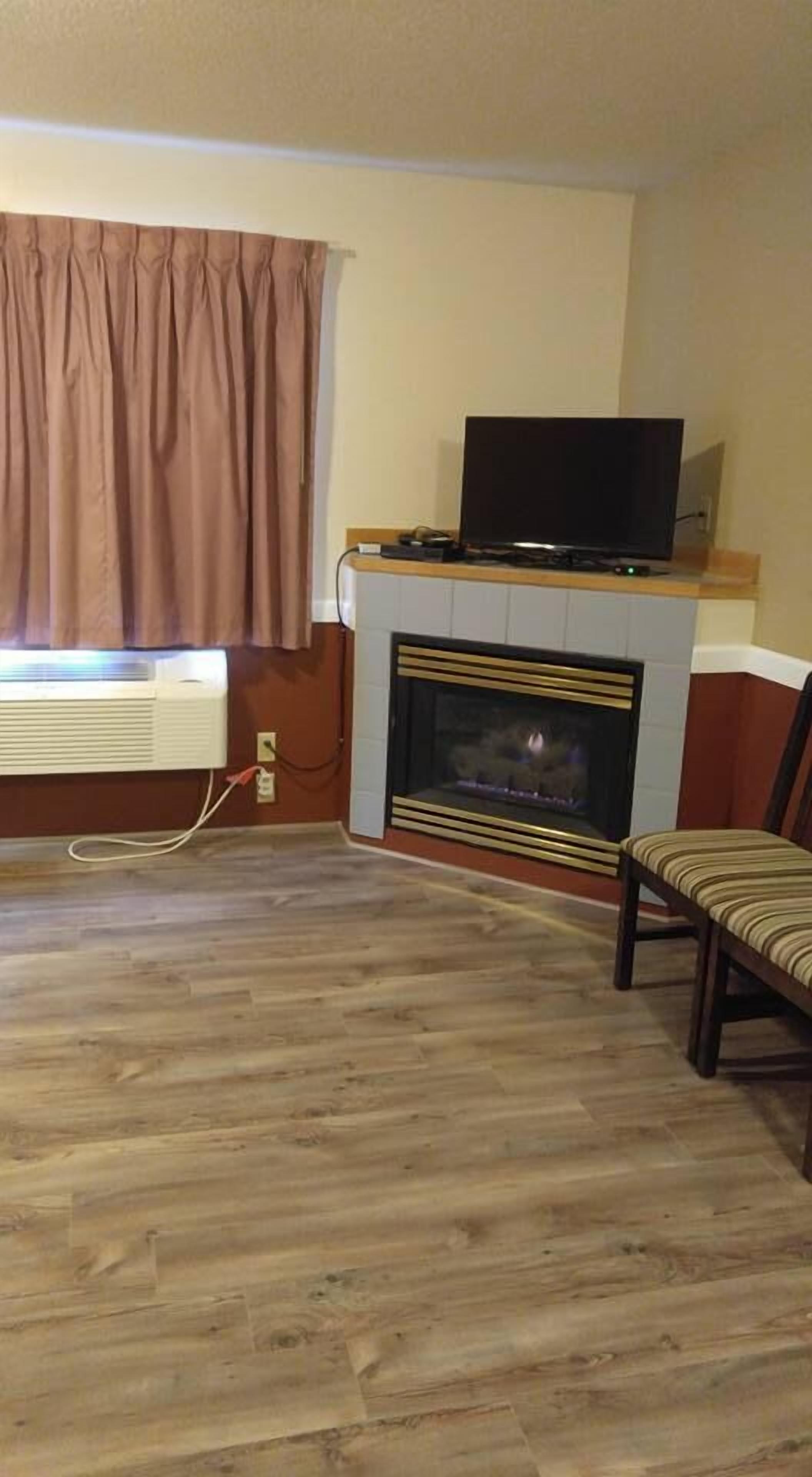 A living room with a fireplace, a television on a stand, and a chair.