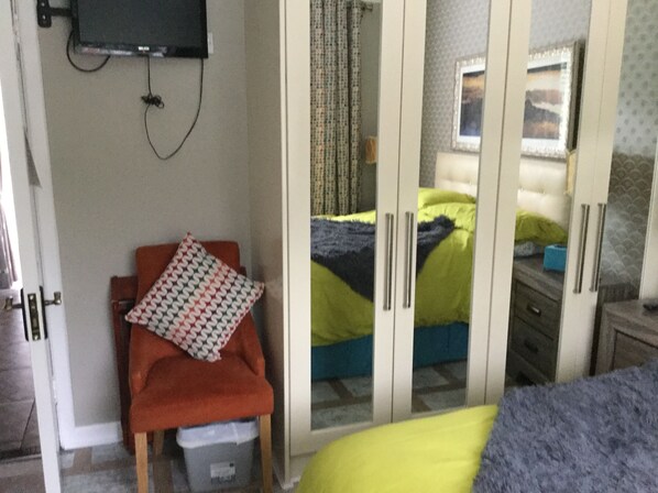 A bedroom with a bed, a chair, a wardrobe, and a television mounted on the wall. - Krakow B&B (Dundalk)