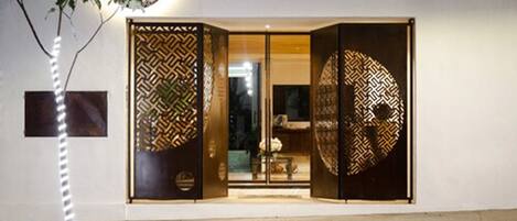 El exterior del Hotel Boutique Casa Los Cántaros, con un diseño moderno, presenta puertas con motivos decorativos y una entrada bien iluminada.