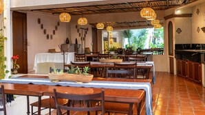 A restaurant with wooden tables and chairs, hanging wicker lamps, and a view of greenery outside. - Casa Los Cantaros Hotel Boutique (Oaxaca)