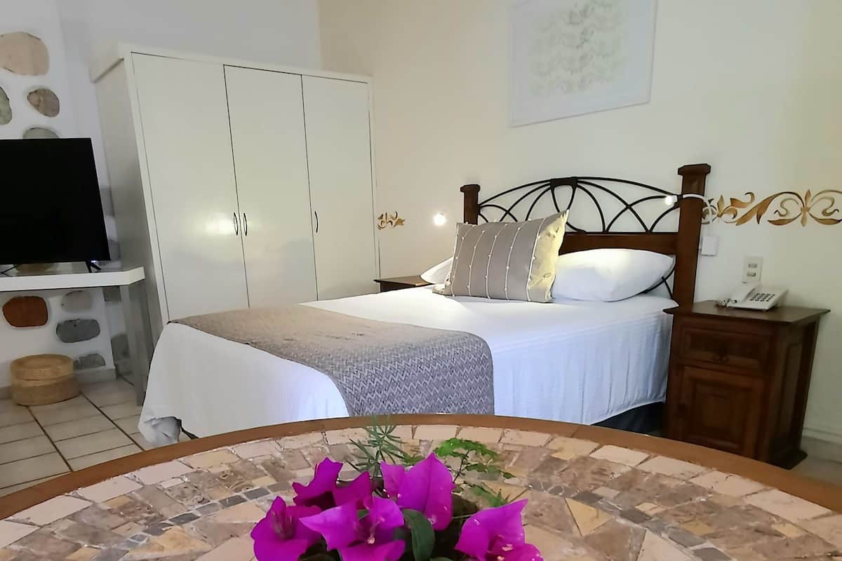 A bedroom with a bed, a nightstand, a television, and a wall-mounted telephone.