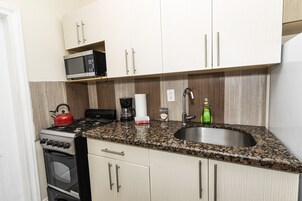 A kitchen with a granite countertop, stainless steel sink, microwave, stove, and oven.