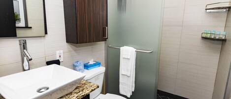 Un bagno moderno con lavabo in marmo, un water, box doccia in vetro e mobile contenitore in legno.