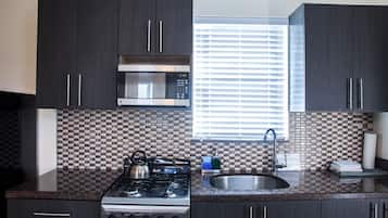 A kitchen with dark cabinets, a microwave, a stove, and a window with blinds.