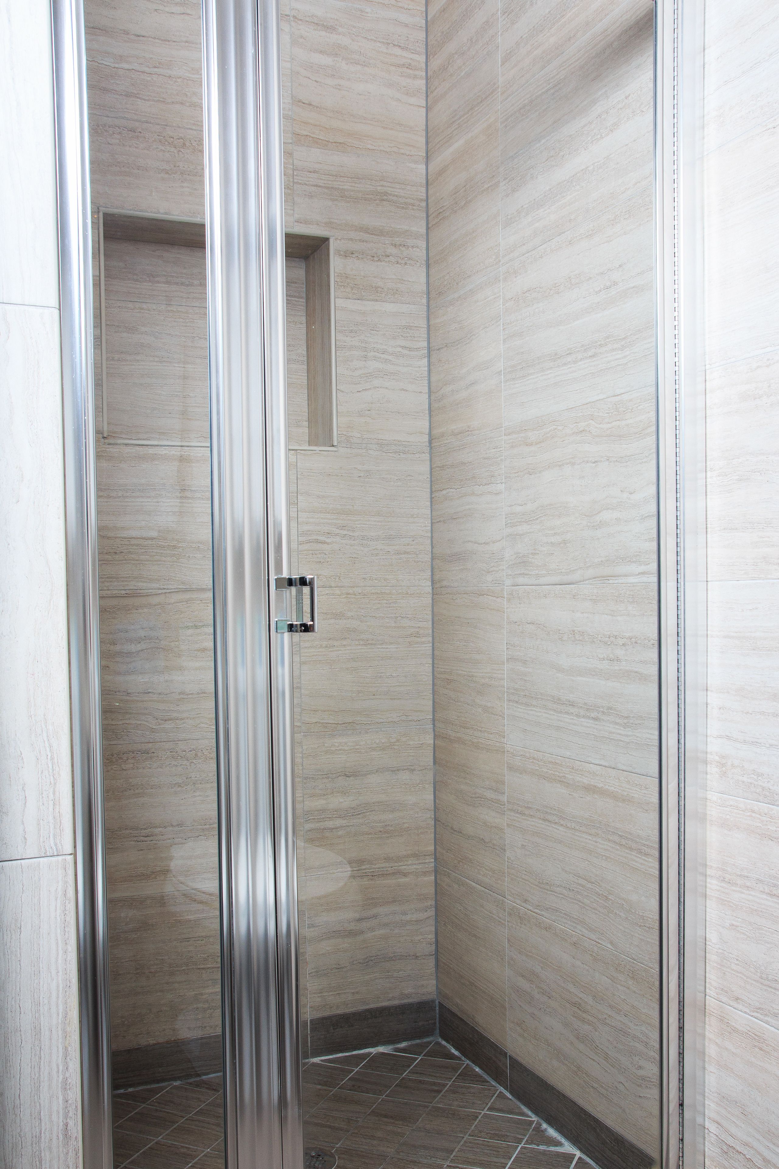 A modern shower enclosure with a glass door and a small window.