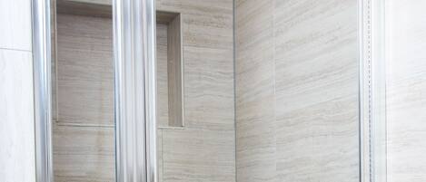 A modern shower enclosure with a glass door and a small window.