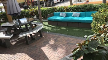An outdoor seating area with a picnic table and a sofa with patterned cushions.