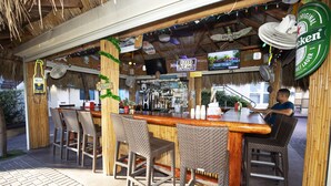An outdoor bar area with wicker chairs, a wooden bar counter, and a Bud Light sign.