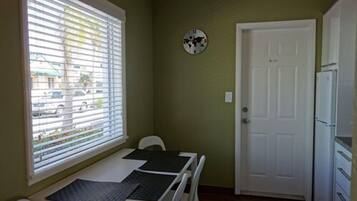 Una habitación pequeña con ventana, puerta y una mesa con una silla.