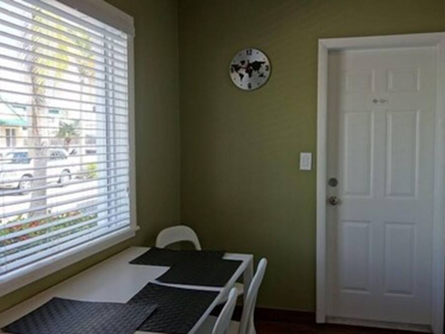 Una habitación pequeña con ventana, puerta y una mesa con una silla.
