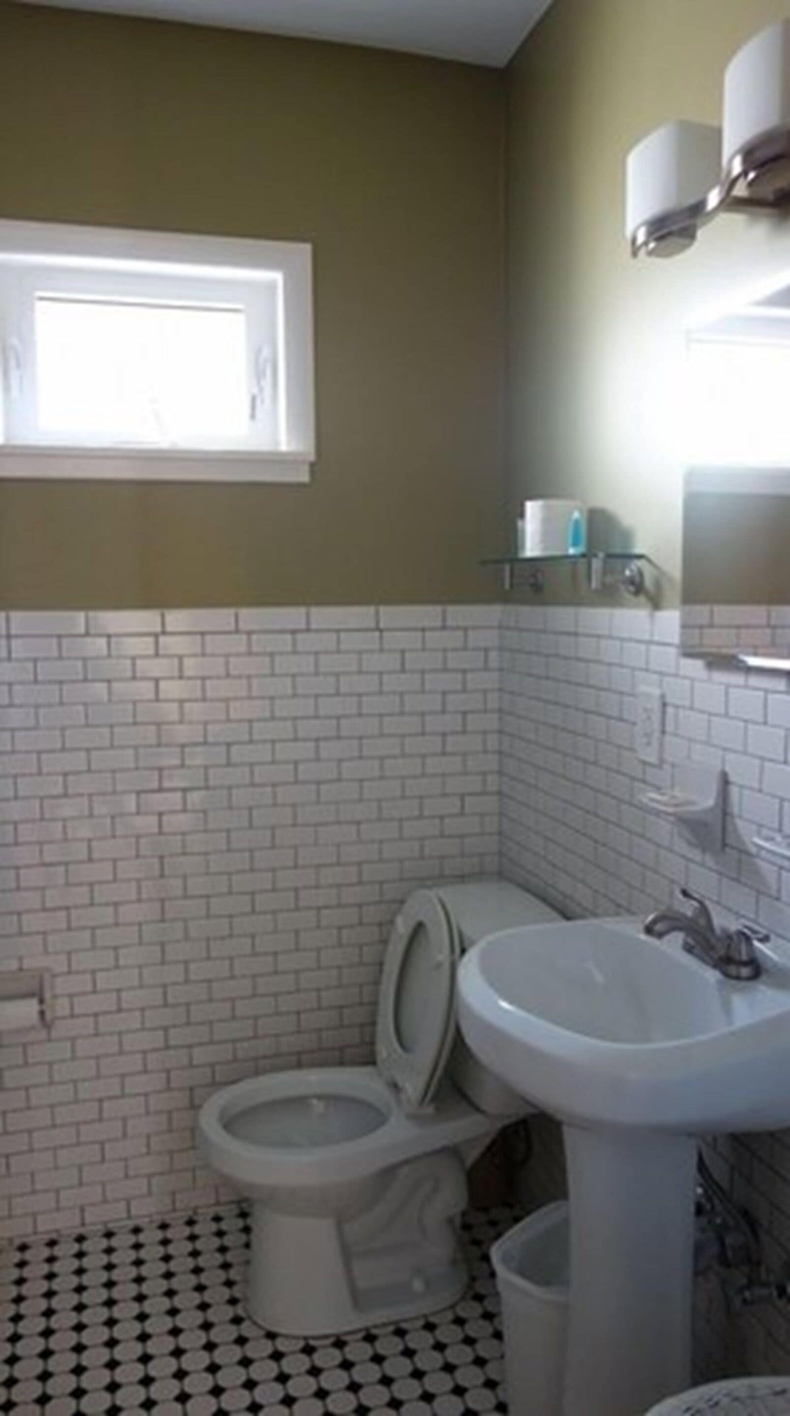 Ein Badezimmer mit Toilette, Waschbecken und einem Fenster.