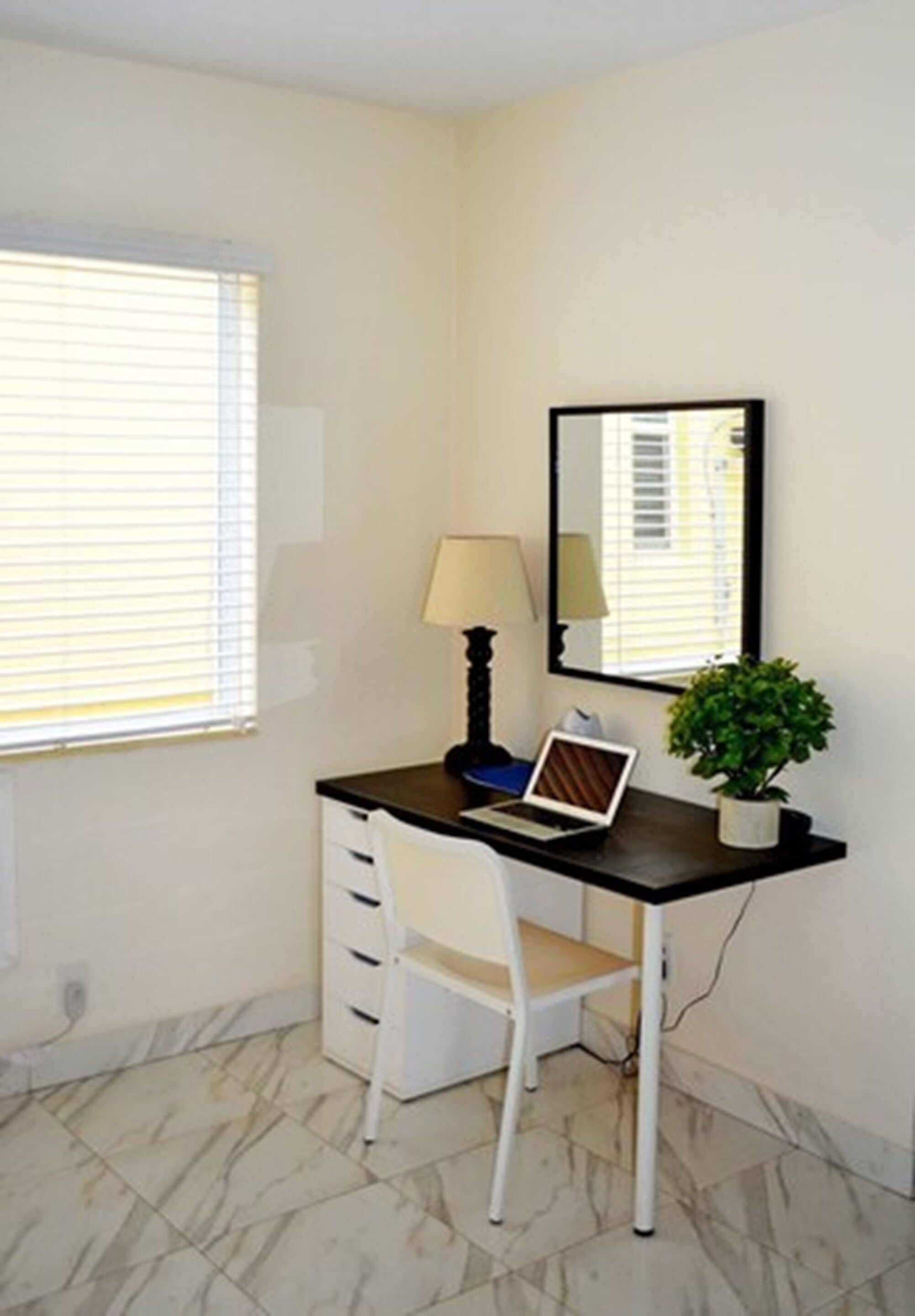 A small, clean room with a desk, chair, and a potted plant.