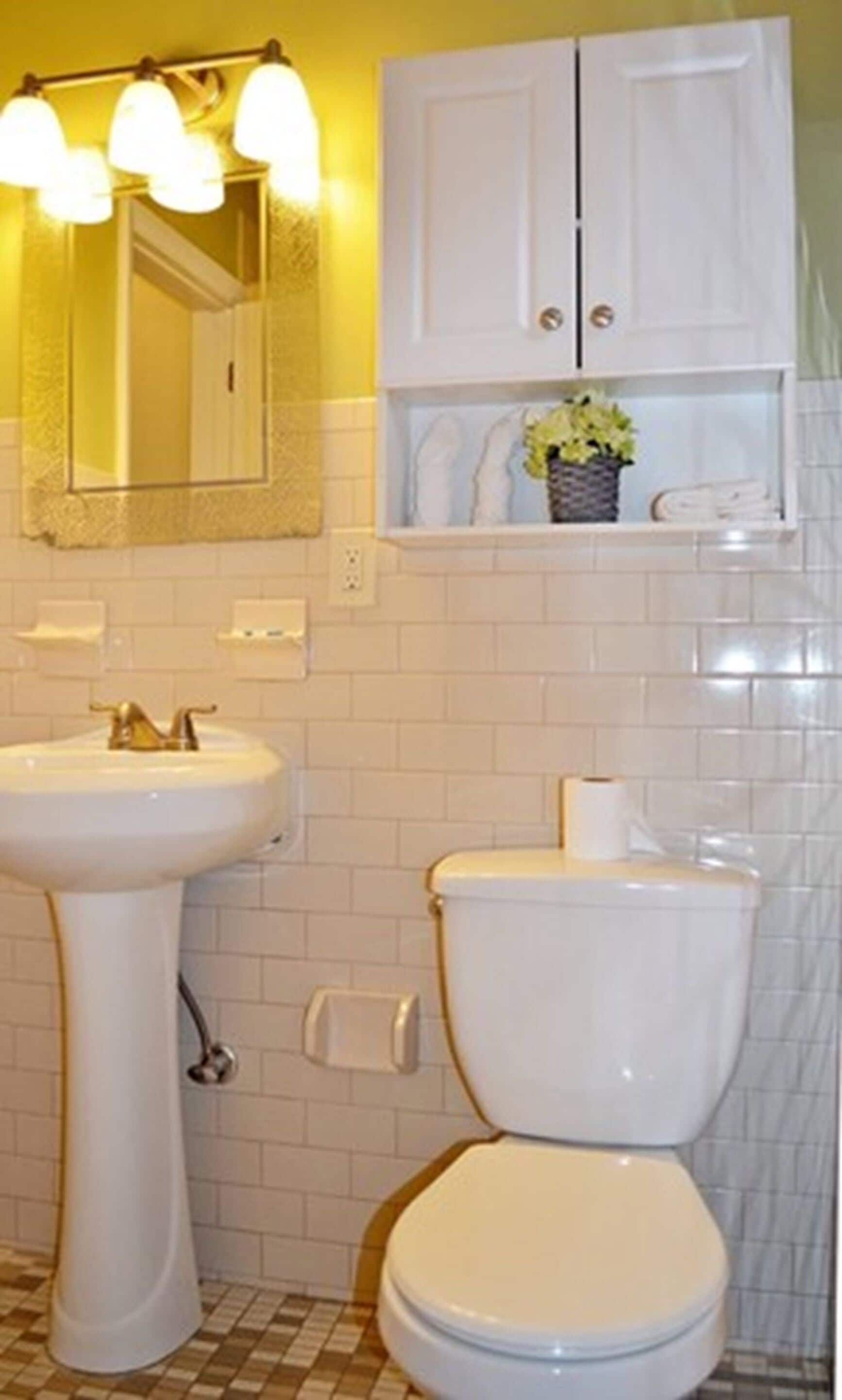 A bathroom with a white sink, a toilet, and a mirror with lights.