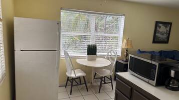 A compact kitchen with a refrigerator, microwave, and a small dining table with chairs.