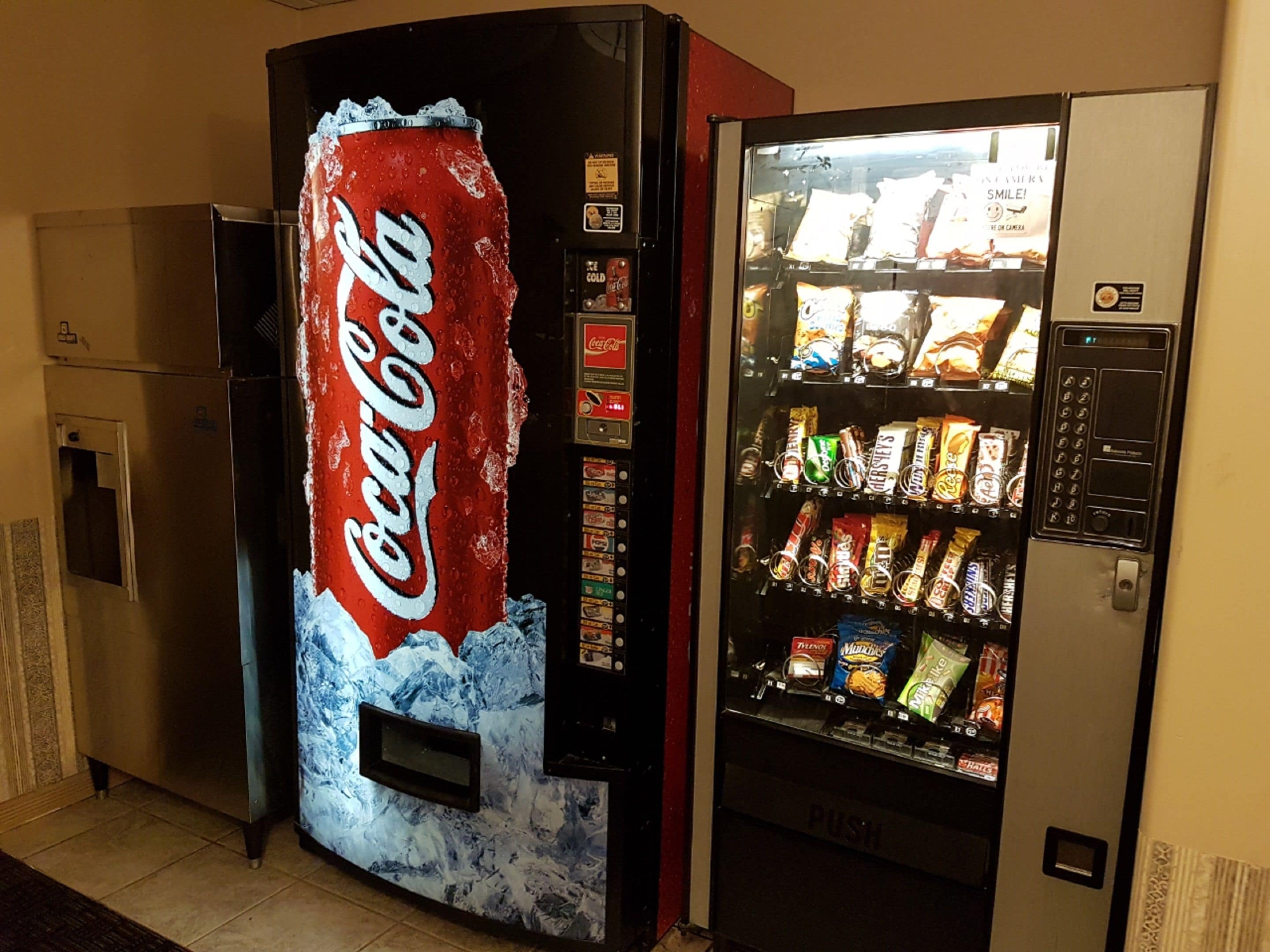 A vending machine with a Coca-Cola logo and a snack vending machine next to it.