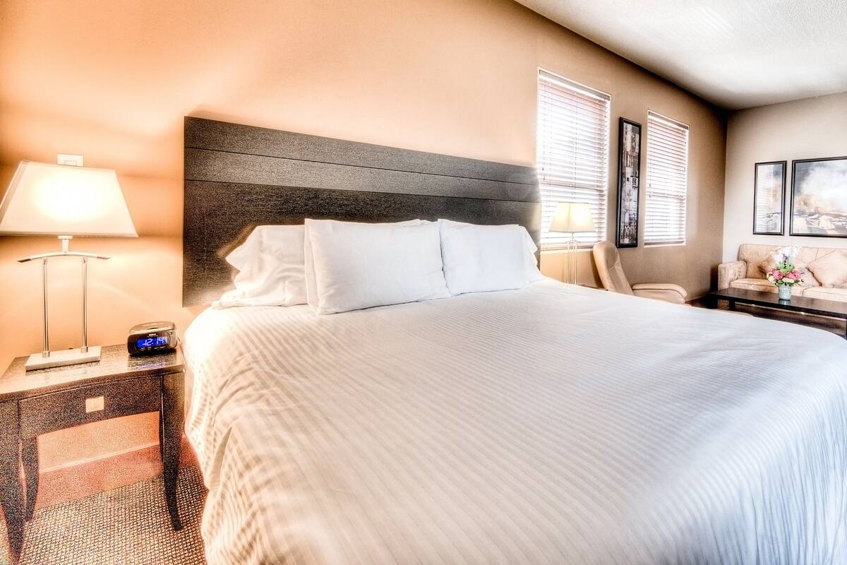 Una camera d'albergo con un letto grande, comodini, una scrivania e un divano.