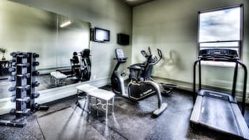 Une salle de sport équipée de machines de cardio, de matériel de musculation et d’un miroir.