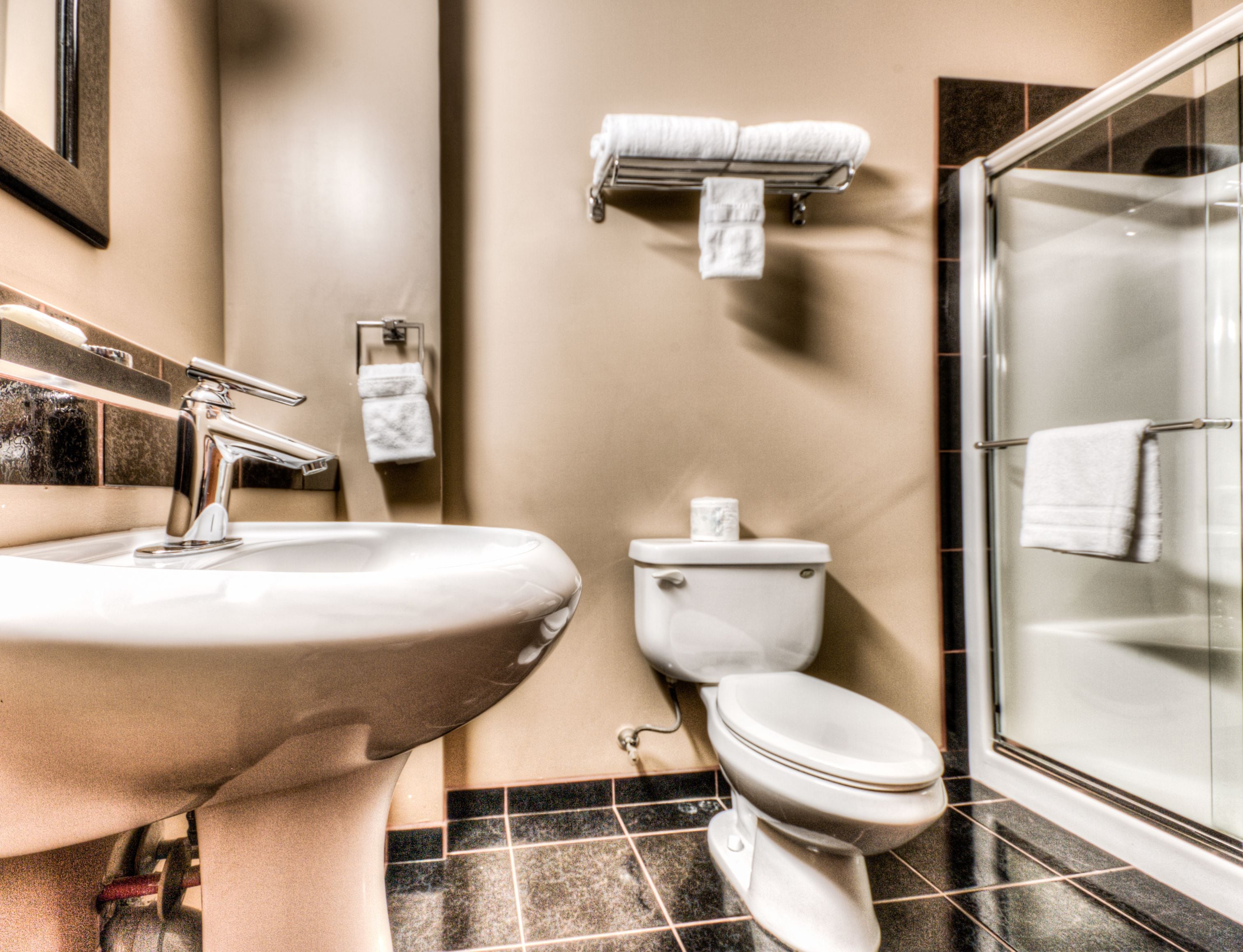 A bathroom with a sink, toilet, and glass shower stall.