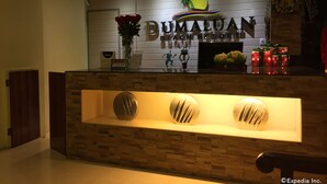 Bancada de recepção no Bumaluan Beach Resort, com logotipo, placa de boas-vindas e objetos decorativos.