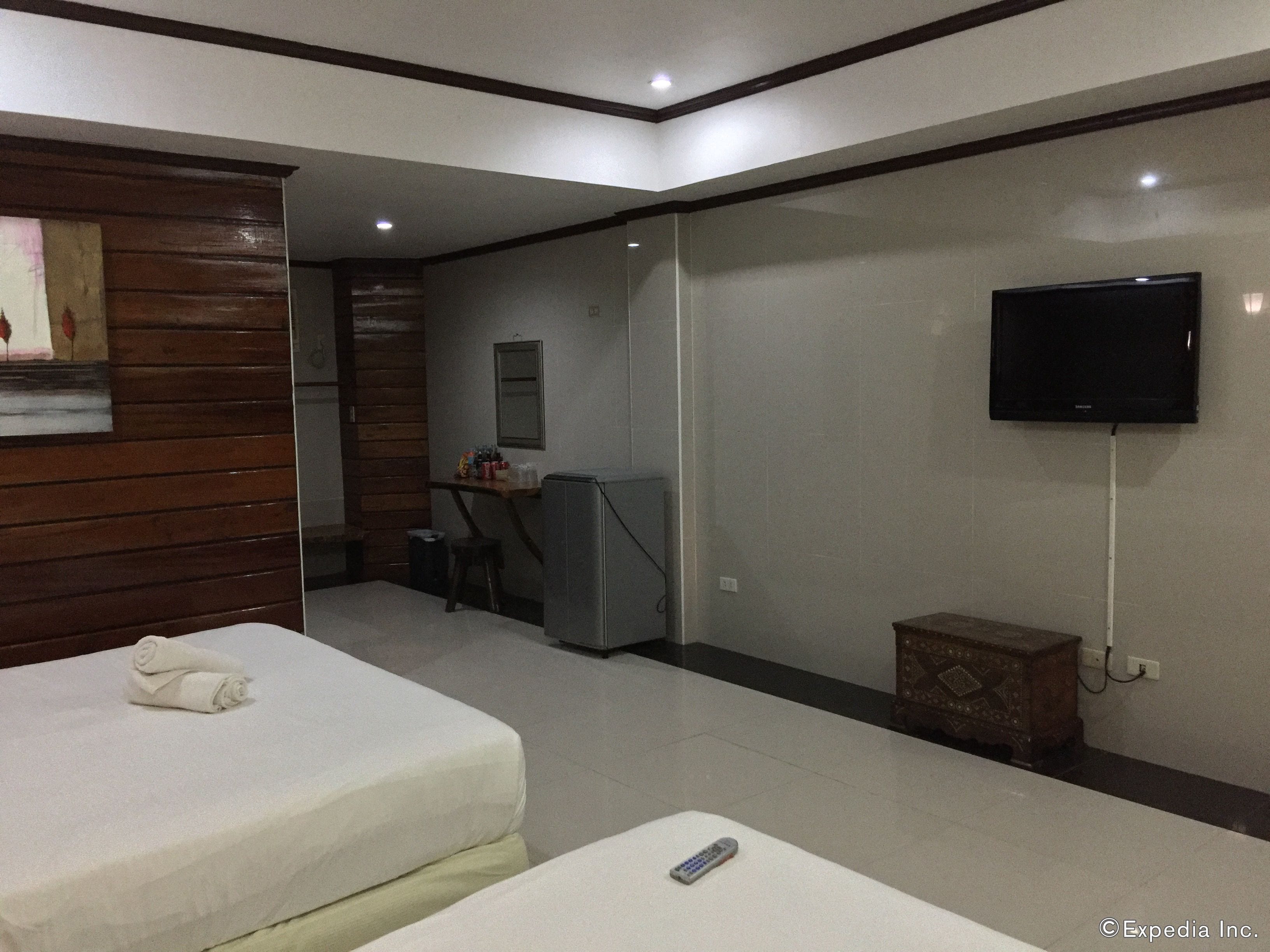 A hotel room with two beds, a desk, a television, and a small cabinet.