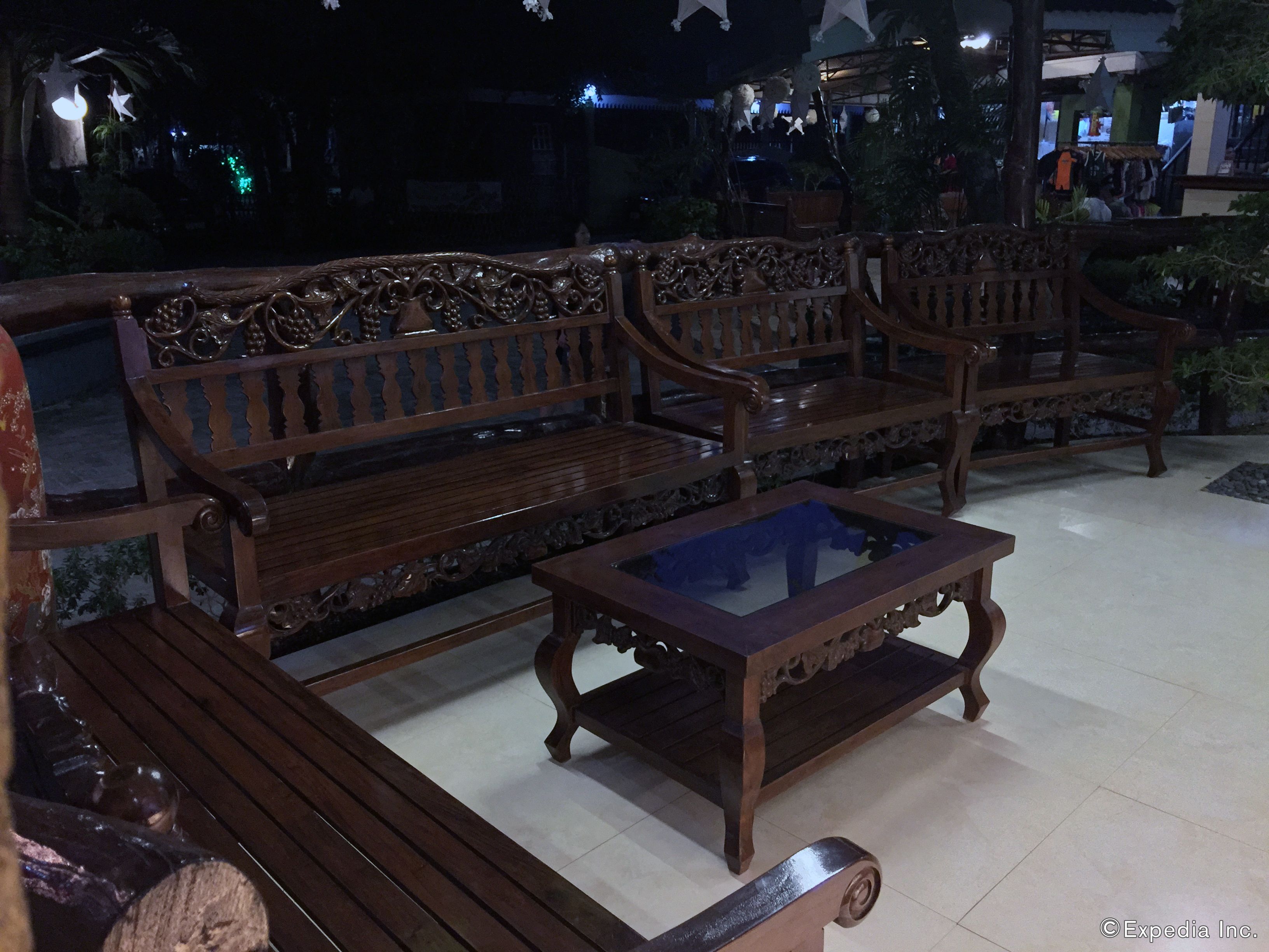A set of wooden benches and a glass-top coffee table in an outdoor area with tiled flooring.