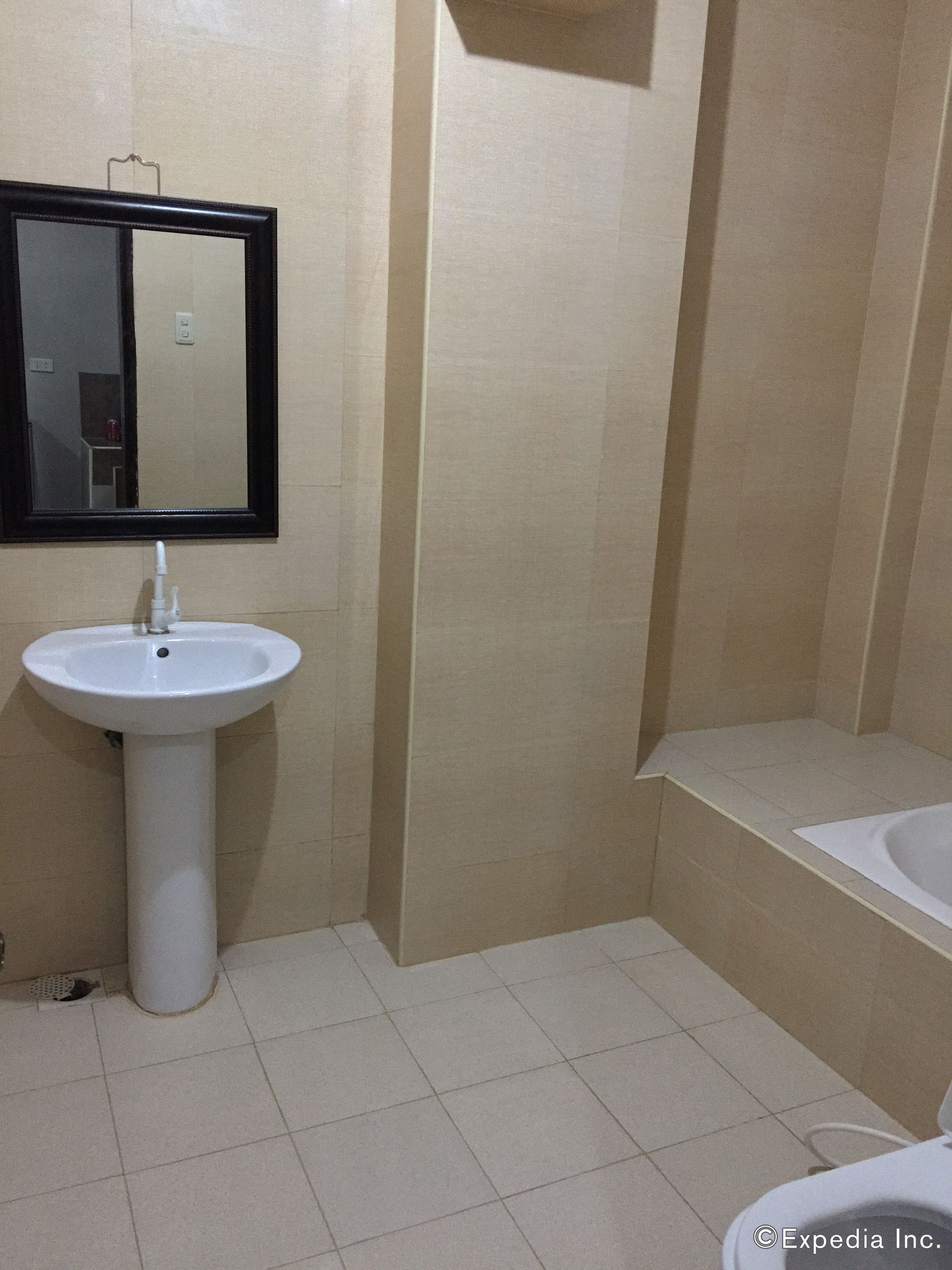 Une salle de bain avec un lavabo sur colonne, un miroir et une baignoire.